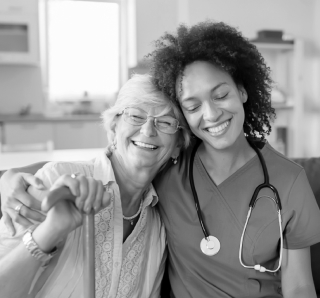 Elderly woman and caregiver embracing.