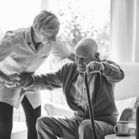  Caregiver helping elderly man stand up.