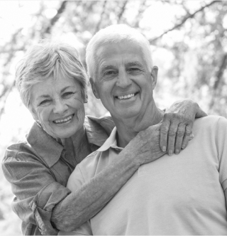 Elderly couple embracing and smiling.